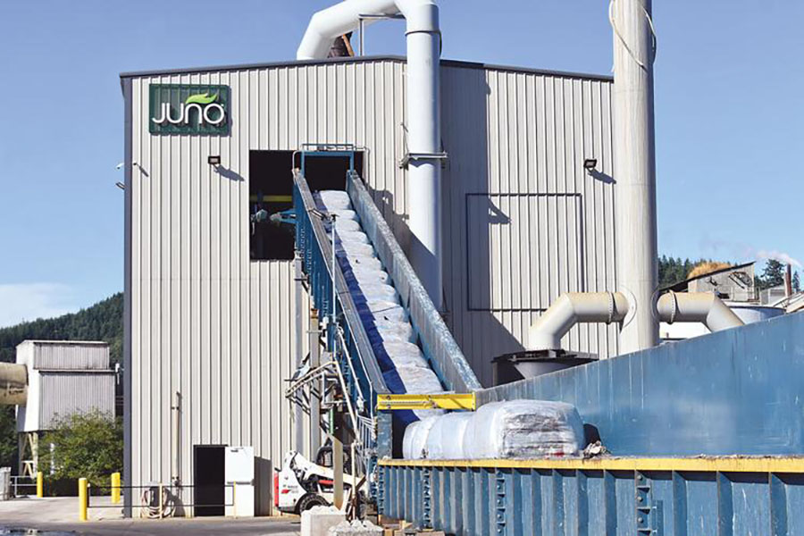 Large bales of shredded garbage coming up a conveyor belt into the Juno facility